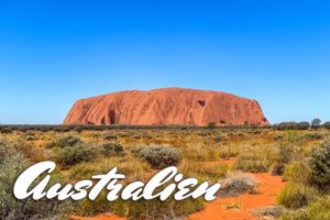 Der Uluru in Australien vor einer Graslandschaft.