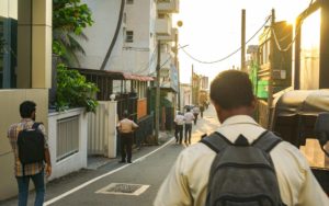 Sri Lanker gehen am Morgen eine Straße in Colombo entlang.