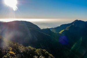 Bergpanorama vor der hell strahlenden Morgensonne, das Tal liegt im Nebel.