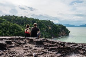 Steffen und Farina sitzen auf einem Felsen an der Küste des Bako Nationalparks.