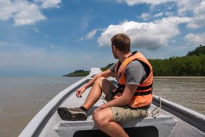 Steffen sitzt auf dem Bug eines Bootes auf dem Tabo Fluss auf dem Weg in den Bako Nationalpark.