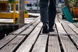 Zwei Beine in der Schrittbewegung beim Spazierengehen auf einem Holzweg des Wasserdorfes.