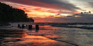 Das rot des Sonnenuntergans spiegelt sich im Wasser am Strand von Miri.
