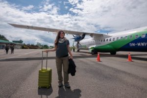 Farina steht vor einem Flugzeug auf dem Rollfeld in Mulu.
