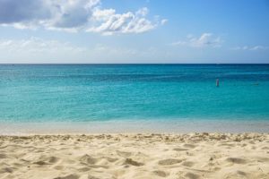 Weißer Sandstrand vor türkisem Wasser. Der Seven Mile Beach ist Karibik pur.
