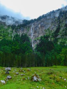 Eine große Felswand ragt auf, ein Wasserfall ist zu sehen.
