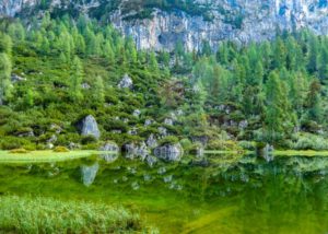 Der Schwarzensee schimmert grünlich dunkel vor den Felsen der Berge.