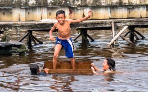Drei Kinder spielen im Fluss in Pontianak auf Borneo.