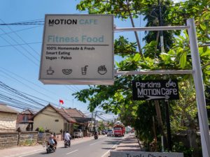 Die Straße in Canggu zeigt das Schild des veganen Restaurants Motion Café.