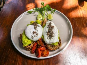 Ein Frühstücksteller mit Avocadobrot und pochiertem Ei.