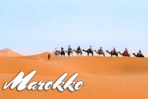 Eine Karawane reitet durch die Wüste Marokkos.